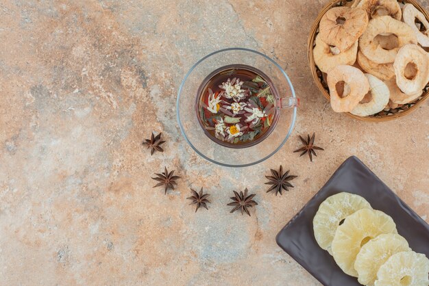 Un panier en bois plein d'ananas séché et une tasse de tisane