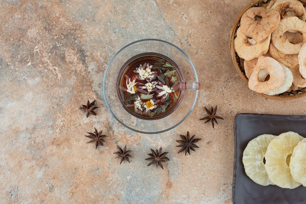 Un panier en bois plein d'ananas séché et une tasse de tisane