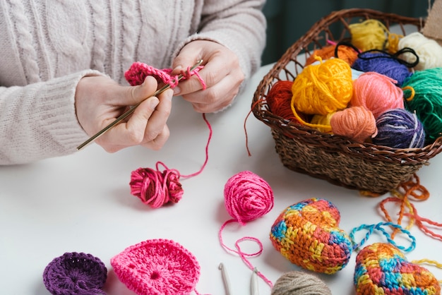 Panier de boules de laine et femme tissant