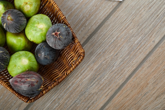 Un panier de figues mûres sur table en bois.