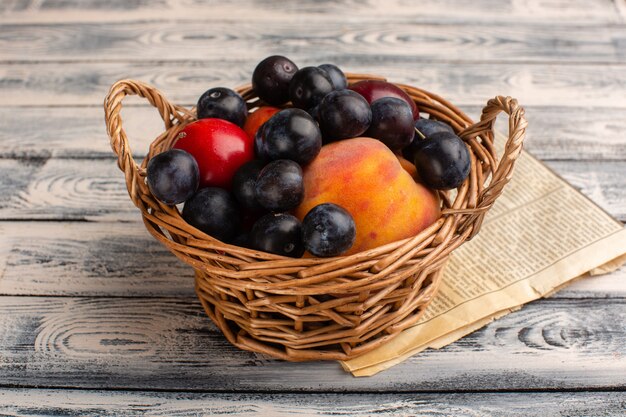 Panier avec fruits prunellier pêches sur bois gris