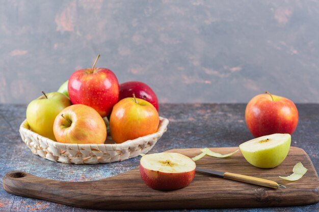 Panier en osier de pommes fraîches colorées sur table en marbre.