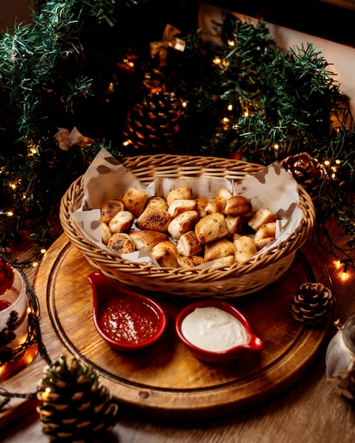 Un panier de paille avec de petits pains à l'ail servi avec de la mayonnaise et de la sauce tomate