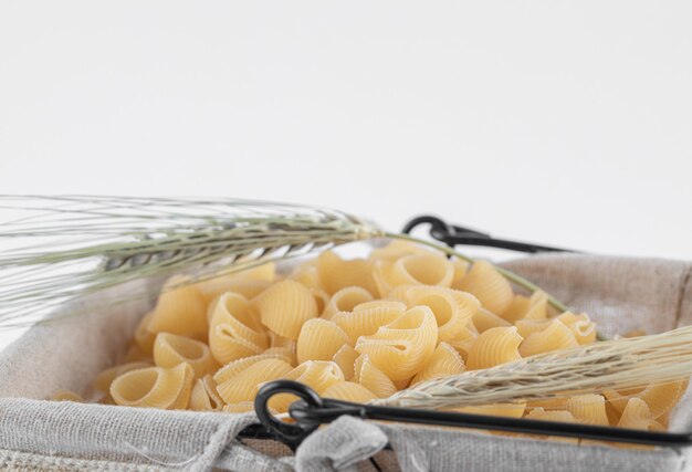 Panier de pâtes crues aux épis de blé sur fond blanc. photo de haute qualité