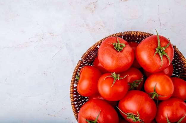 Panier plein de tomates sur une surface blanche