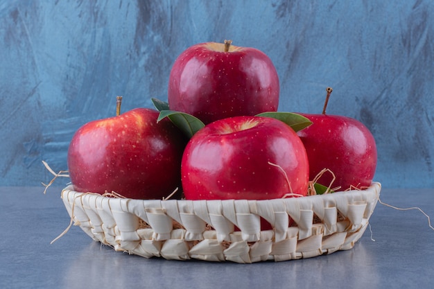 Un panier de pommes et de feuilles sur la surface sombre