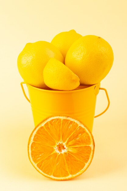 Un panier vue de face avec des citrons en tranches fraîches entières moelleuses et juteuses avec tranche d'orange sur le fond de couleur crème