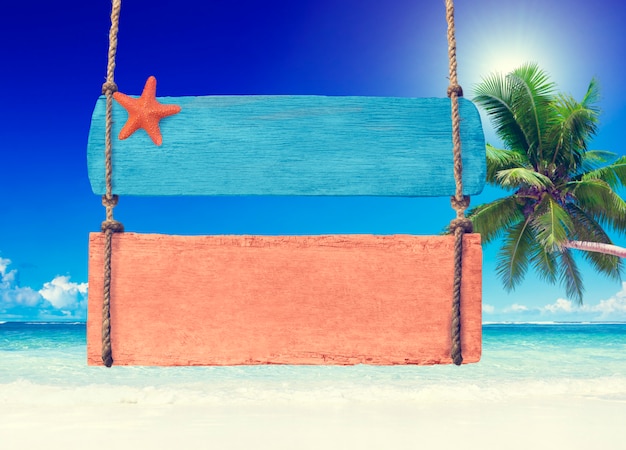 Panneau en bois coloré suspendu à une plage tropicale