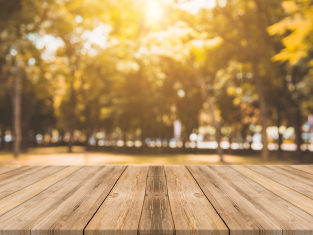 Photo gratuite panneau de bois table vide devant un fond flou. perspective table en bois brun sur les arbres floues en fond de forêt - peut être utilisé maquette pour l'affichage ou le montage de vos produits. saison de l'automne.