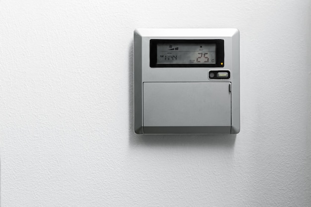 Le panneau de commande de climatisation et de chauffage de l'appartement et du bureau est situé sur un mur blanc