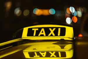 Photo gratuite panneau noir et jaune de taxi la nuit placé au-dessus d'une voiture