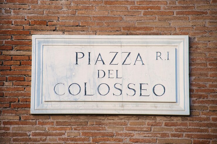 Photo gratuit le panneau de la piazza del colosseo sur un mur de brique