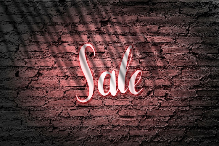 Photo gratuit un panneau de vente rouge néon sur un mur de brique