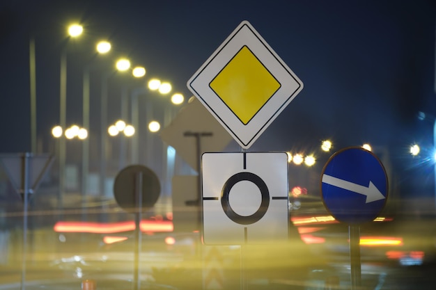 Panneaux routiers ronds-points avec des voitures floues sur la circulation dans les rues de la ville la nuit. concept de transport urbain