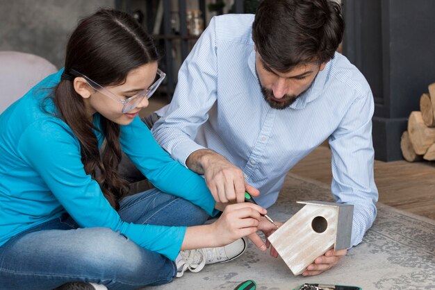 Photo gratuite papa enseigne à une fille à construire une maison d'oiseaux