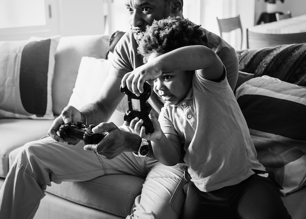 Photo gratuite papa et fils jouent à des jeux dans le salon