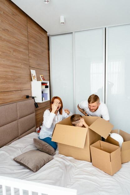 Papa, maman et petit fils jouent dans la chambre avec des boîtes en papier