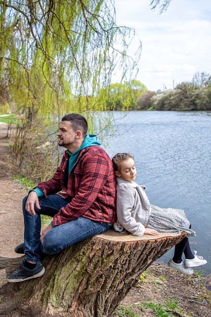 Papa Et Sa Petite Fille Sont Assis Dans La Forêt Au Bord De La Rivière Au Début Du Printemps Et Profitent De La Nature.