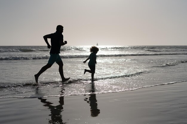 Papa avec la silhouette d'un garçon enfant en mer ou en océan. week-end journée en famille. papa et enfant s'amusant à l'extérieur. enfance et parentalité. vacances en famille. activité estivale. père et fils courant sur la plage.