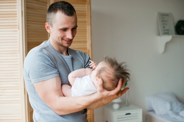 Photo gratuite papa souriant tenant bébé sur les mains