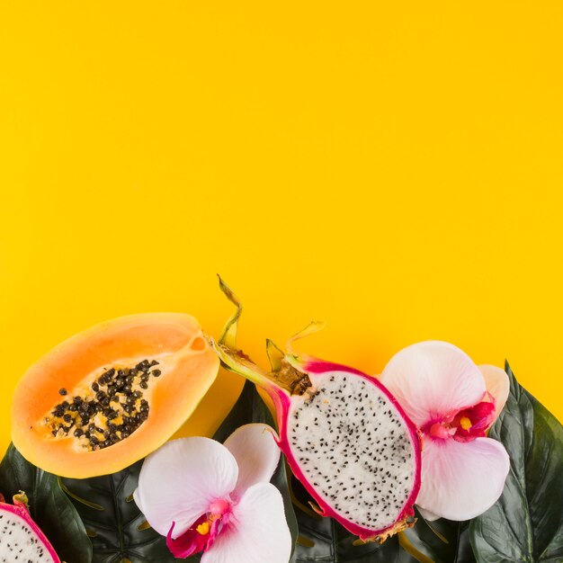 Papaye; fruit du dragon; feuilles et fleur d&#39;orchidée sur fond jaune