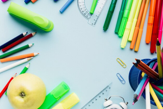 Papeterie d&#39;école colorée dispersée autour d&#39;un espace vide sur le bureau bleu