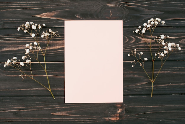 Papier blanc avec des branches de fleurs sur la table