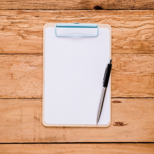 Photo gratuite papier blanc sur le presse-papiers avec stylo à bille sur le bureau en bois