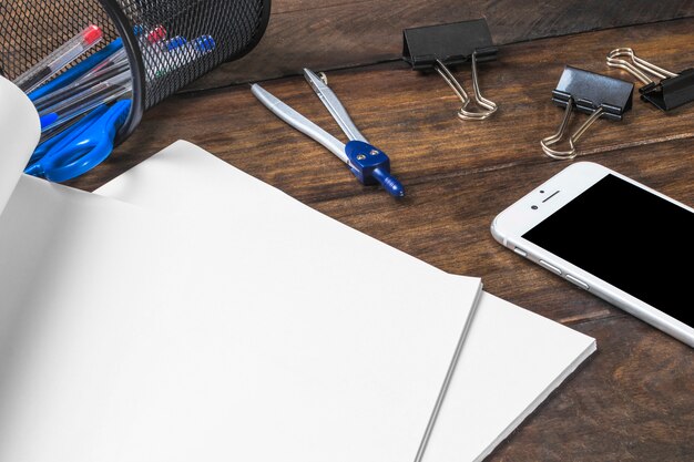 Papier blanc vierge avec des papeteries et smartphone sur table en bois
