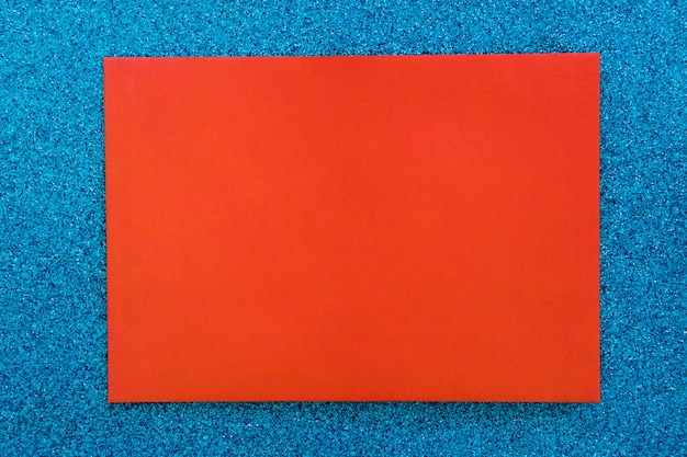 Papier carton rouge sur fond de paillettes bleu