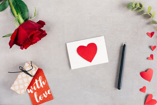 Papier avec coeur près de tag, stylo et fleur