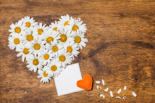 Photo gratuite papier entre un coeur ornemental de fleurs blanches et un jouet orange