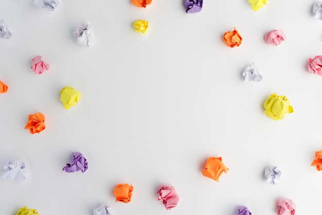 Papier froissé multicolore disposé dans un cadre circulaire sur fond blanc