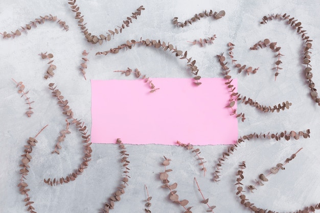 Photo gratuite papier rose entre un ensemble de brindilles de plantes sèches