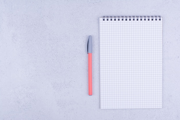 Papier vérifié vierge blanc avec un stylo sur une surface grise