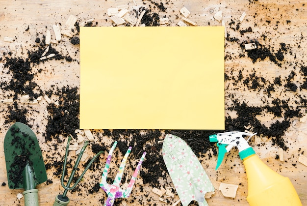 Photo gratuite papier vide blanc jaune sur le sol avec des équipements de jardinage