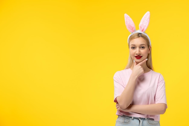 Pâques adorable jolie jeune fille blonde avec des oreilles de lapin souriant avec la main sur le menton