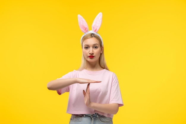 Pâques belle blonde adorable fille avec des oreilles de lapin rose et rouge à lèvres rouge montrant le panneau d'arrêt