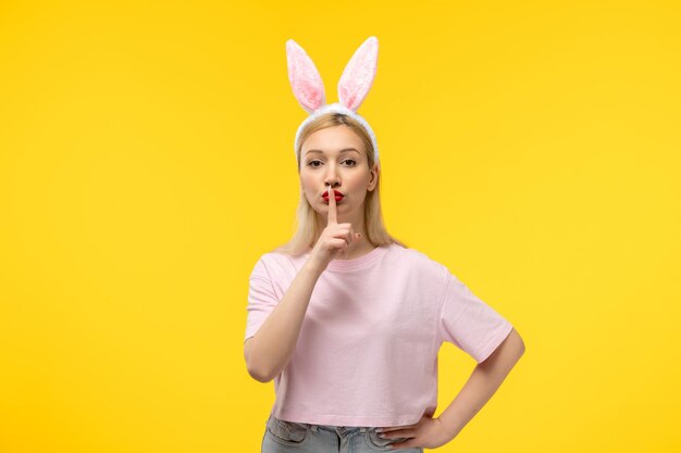 Pâques belle jolie fille blonde avec des oreilles de lapin montrant un geste de silence