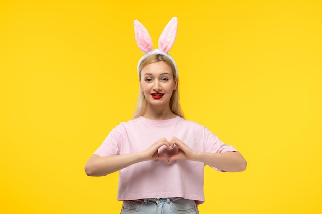 Photo gratuite pâques belle jolie fille blonde avec des oreilles de lapin tenant des mains en forme de coeur