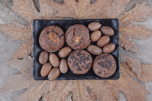 Un Paquet De Biscuits Et De Noix De Pécan Sur Un Plateau Et Un Bouquet De Feuilles De Platane Sur Marbre