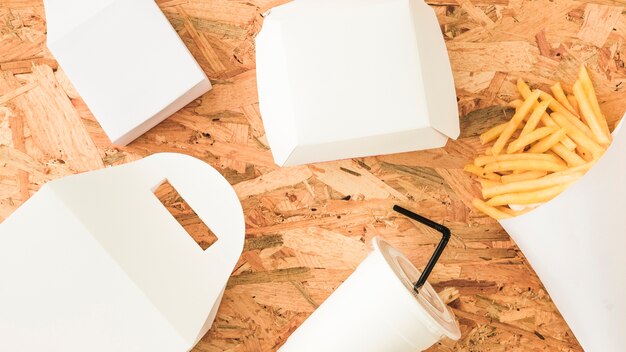 Paquet blanc; boisson jetable et frites sur fond en bois