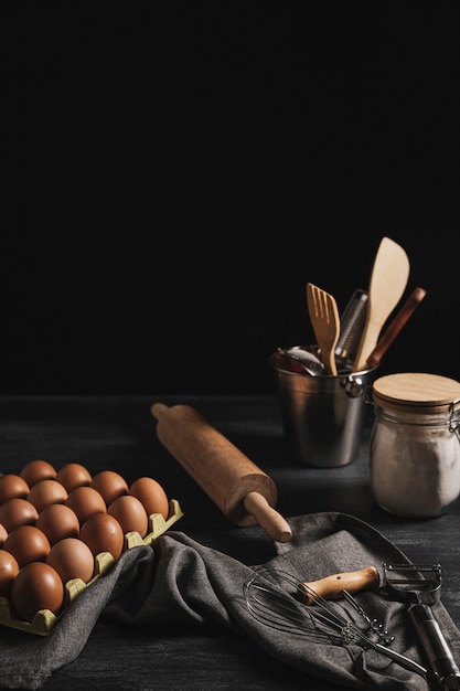 Photo gratuite paquet d'oeufs à angle élevé à côté des ustensiles de cuisine