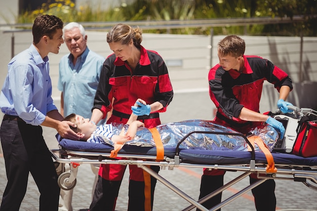 Photo gratuite les paramédics examinent un garçon blessé