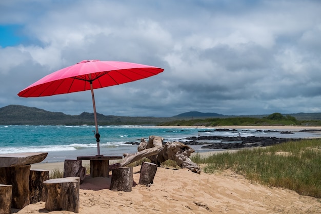 Parapluie rouge fournissant de l'ombre pour les personnes sur la plage dans les îles Galapagos, Equateur