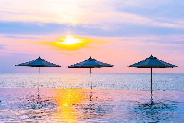 Parasol et chaise autour de la piscine au bord de la mer, au lever ou au coucher du soleil