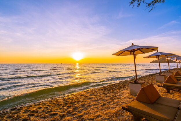 Parasol et chaise avec oreiller autour du magnifique paysage de plage et de mer