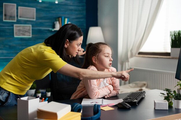 Parent aidant sa fille à faire ses devoirs de mathématiques à l'aide de la plate-forme d'apprentissage en ligne en classe pendant la quarantaine du coronavirus. Enfant intelligent étudiant la littérature élémentaire ayant une leçon d'école en ligne