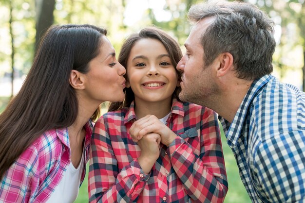 Parent embrassant leur jolie fille dans le jardin