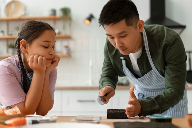 Photo gratuite un parent enseigne à son enfant à faire du sushi.